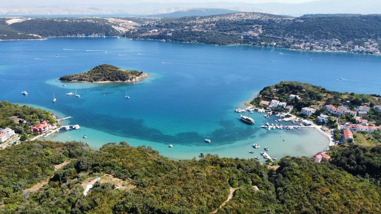 A captivating aerial view of the scenic bay in Rab, Croatia featuring turquoise waters and lush landscape.