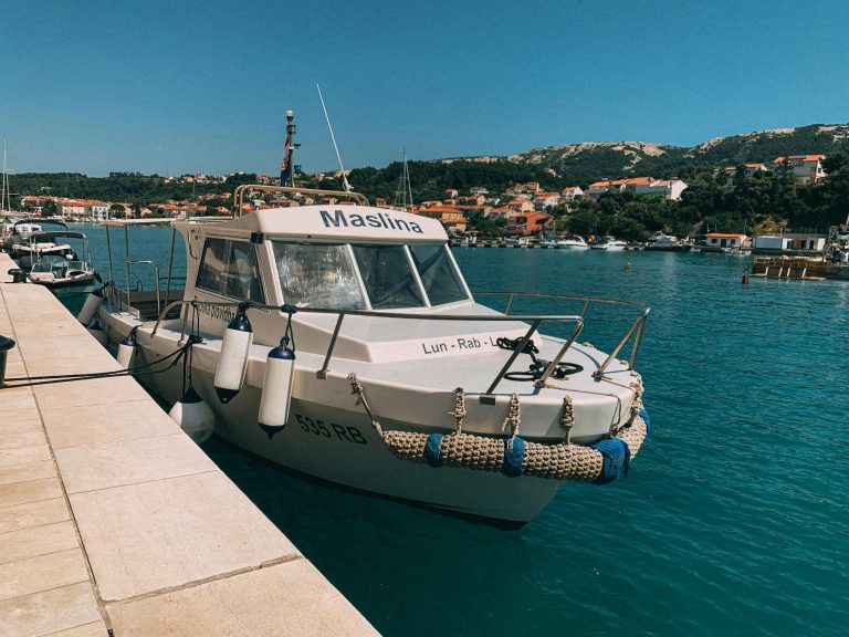 A motorboat named Maslina moored at a sunny harbor in Croatia, clear waters and scenic coastline.
